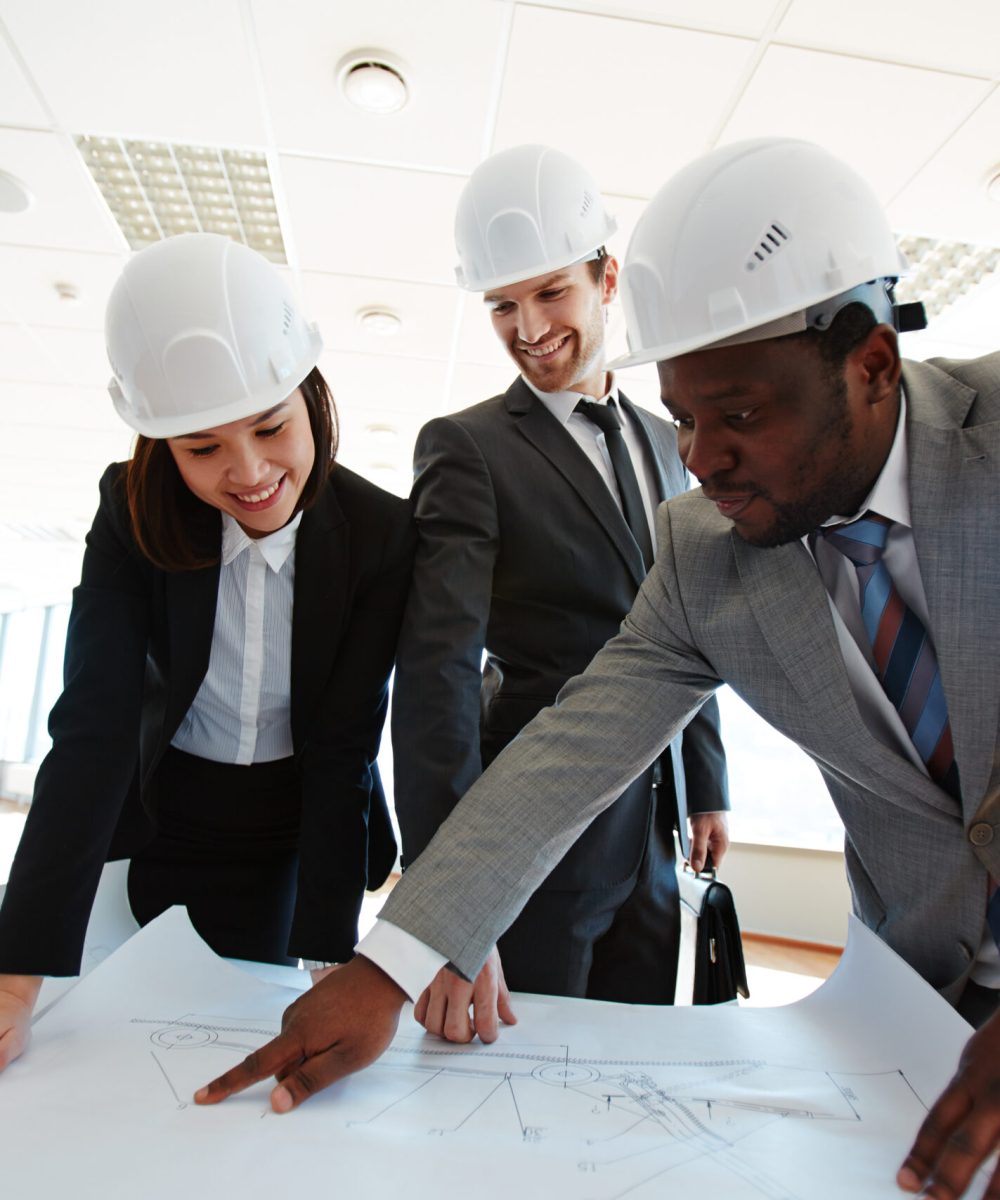 Confident architects in protective helmets looking at blueprint